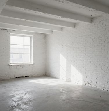 A bright, airy renovated loft space with white exposed brick walls and high ceilings, showcasing the transformation from a neglected attic to a premium living area.