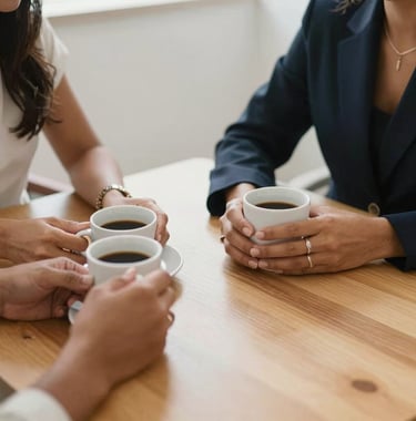 A detail shot of two South American / Brazilian women talking over a minimalist wooden table, focus on their hands and coffee cups, conveying connection, empathy, and professional coaching.