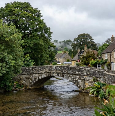 A traditional stone bridge over a clear river in a village like Burnsall. Green trees overhanging the water and mist white clouds above. A peaceful Northern European / British / Yorkshire scene.