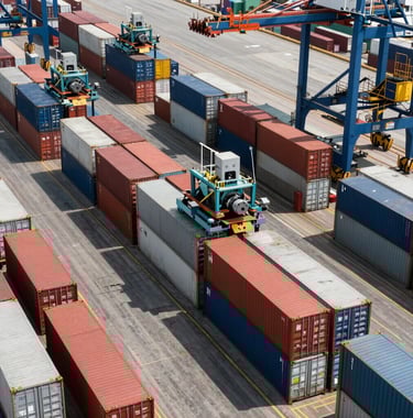 A high-angle view of rows of colorful shipping containers at a port terminal, industrial landscape with specialized machinery, bright daylight, emphasizing efficiency and sea freight solutions, Global Business setting.