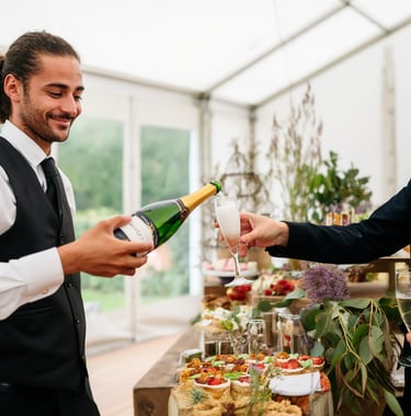Un serveur professionnel verse du champagne à un invité lors d'une réception avec traiteu