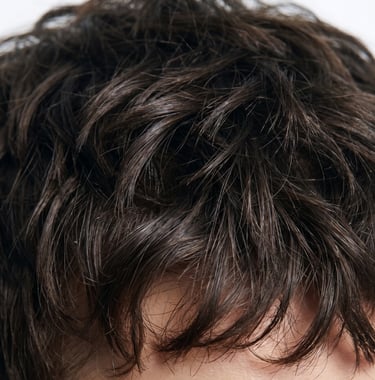 Close-up of short, dark brown wavy hair with natural texture and messy styling.