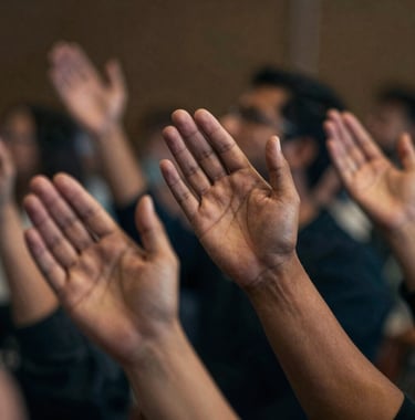A close-up, spiritually profound image of hands reaching upward during a service. The lighting is cinematic and dramatic, using a palette of #0D131C and #D8B863. The focus is sharp on the expression of faith.
