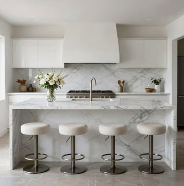 Symmetrical shot of an expansive white marble kitchen island with grey veining, featuring designer bar stools and minimal floral arrangement, soft natural daylight in a luxury Californian setting.