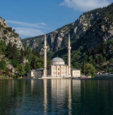 A serene shot of Uzungöl lake with its famous mosque, surrounded by steep mountain walls and pine trees. The water reflects the sky blue and green colors of the landscape.