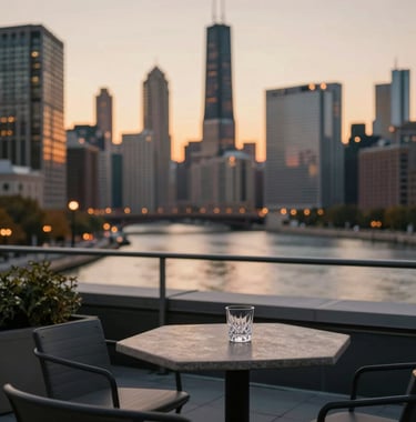 A private rooftop terrace overlooking the Chicago river at sunset. Modern outdoor seating, a small stone table with a crystal glass, and the silhouettes of skyscrapers in the background. The color palette emphasizes #3B5249 and warm amber sunset tones.
