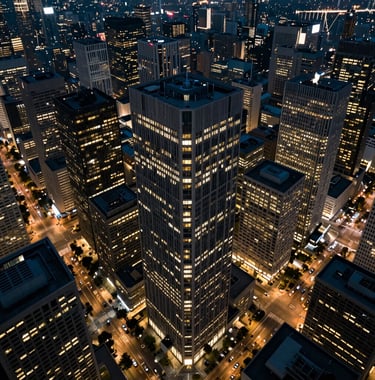 An aerial view of a central business district at dusk, office lights appearing as muted gold dots against charcoal-colored buildings, institutional and controlled atmosphere, International / Global.