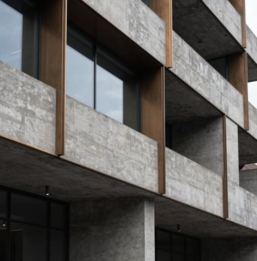 A sharp architectural detail of a modern brutalist concrete structure with bronze accents and dark glass, high contrast deep charcoal shadows, International / Global professional setting.