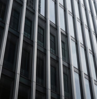 A minimalist, low-angle shot of a modern architectural facade in a North American city, featuring sharp silver geometric lines against a dark charcoal glass exterior, symbolizing structured business growth.