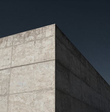 Minimalist architecture showing a sharp corner of a concrete building against a dark charcoal navy sky, symbolizing strength, structure, and precision.