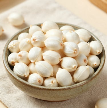 A bright, clean lifestyle photograph of premium white Makhana overflowing from a rustic ceramic bowl placed on an off-white linen cloth, with soft natural light highlighting the purity and quality of the product.