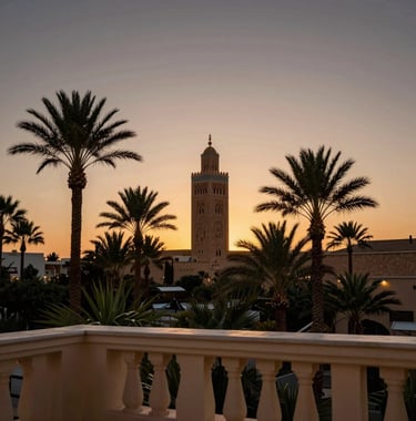 Sunset view over the palms of Marrakech from a luxury Ivory balcony. The silhouette of the Koutoubia is visible against a Charcoal and Bronze sky.