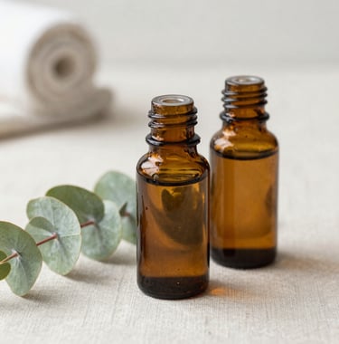 Close-up photography of organic essential oils in amber glass bottles and fresh eucalyptus sprigs resting on a light neutral linen surface in a tranquil San Diego spa environment.