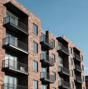 A detailed shot of a sleek North American / US urban residential development, showing modern brickwork and steel balconies under a clear blue sky. The composition is clean and emphasizes long-term value.