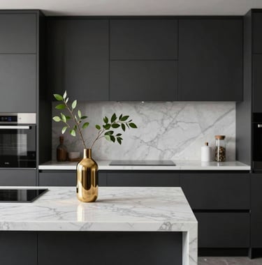 A minimalist, modern kitchen area with charcoal black cabinetry and pearl white marble countertops. A single gold vase with a green branch sits on the island, symbolizing clean and premium design.