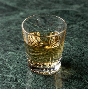 Detail shot of a crystal glass reflecting golden light on a deep green marble surface. The atmosphere is mysterious and clean, representing mental clarity and focus. Professional architectural photography style.