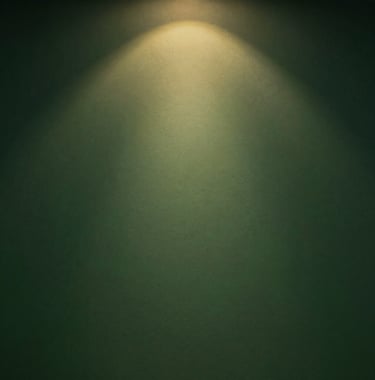 A detailed texture photograph of a dark petroleum green wall with a subtle matte finish, illuminated by a warm, golden focused light beam. Professional architectural photography style, serene and premium vibe.