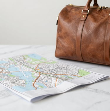 A close-up of a high-quality leather travel bag and a map spread across a clean white marble surface.