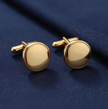 Close-up of a pair of solid gold cufflinks and the edge of a bespoke navy blue suit sleeve, reflecting high-end Southern European craftsmanship.