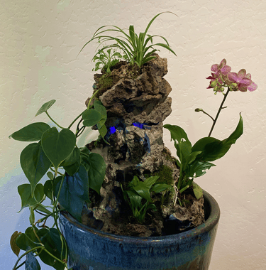 Indoor waterfall sculpture with sculpted stone, orchid, philodendron, and spider plant