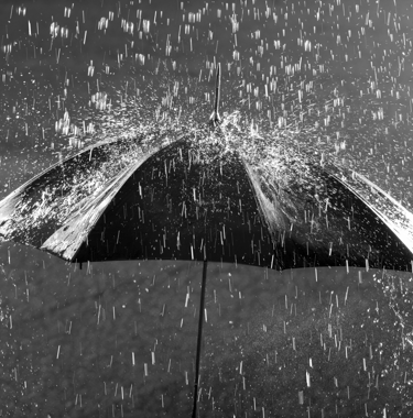 a black and white photo of an umbrella in the rain