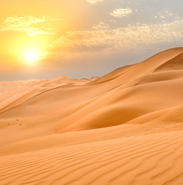 sand dunes in the desert with the sun in the sky