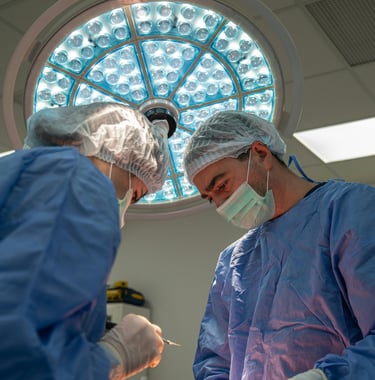 Surgeons performing a surgical procedure under a bright LED medical light in a sterile operating room.