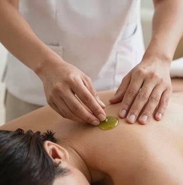 Close-up shot of hands of a professional Southeast Asian / Indonesian therapist gently applying organic green tea oil onto a client's shoulder in a peaceful and professional atmosphere.