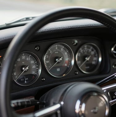A close-up of a classic luxury car's interior, showing the leather dashboard and silver chrome dials, capturing a sense of timeless strength and modern elegance.