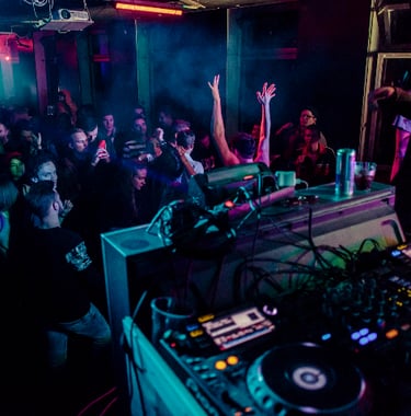 a dj spinning tunes in a nightclub on Pioneer CDJ turntables