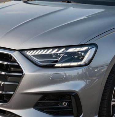 Detailed close-up shot of a modern car's front LED headlight and radiator grille, reflecting silver and chrome details, professional studio lighting, clean and sharp automotive photography.