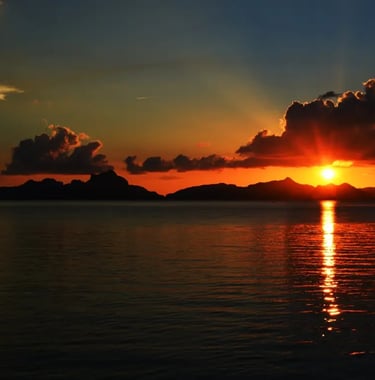 Traditional boat sailing in El Nido bay during a golden sunset dinner cruise