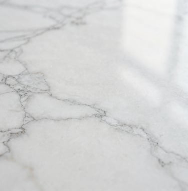 Detail of a white marble surface with light reflecting, soft and airy aesthetic, high-end branding mood.