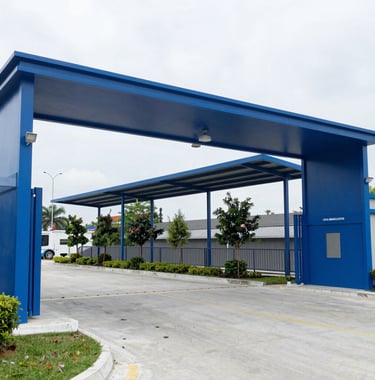 A blue modern industrial entrance gate with commercial signage and a construction yard view.