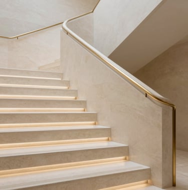 Close-up detail of high-end interior architecture: a minimalist staircase made of cream stone with integrated LED lighting and gold railings. Professional architectural photography, clean and exclusive feel.