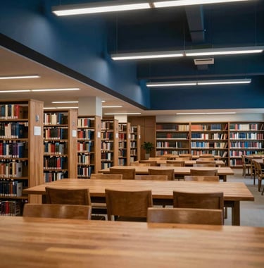 A serene photograph of a university library's study hall. High ceilings, long wooden tables, and rows of books. Soft, even lighting creates a space of academic excellence. Dark navy blue accents.