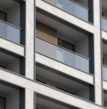 A close-up architectural detail of a luxury multi-dwelling development. The image showcases high-quality masonry, precision timber slats in #C8B8A3 tones, and sleek black steel frames (#212121). The composition is minimalist and high-contrast, emphasizing structural quality and bespoke craftsmanship.