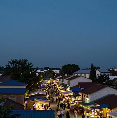 A panoramic view of a local village market at dusk. String lights glowing warmly. A sense of tranquil discovery. The sky is a deep #3E6B7A.
