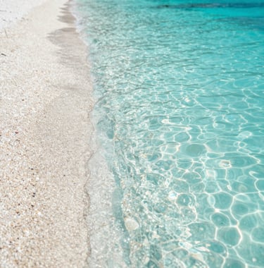 A high-quality photo of a hidden beach with turquoise water and smooth pebbles. The lighting is bright and natural. The colors include #A8C9CF and #F7F9FA. Authentic travel vibe.