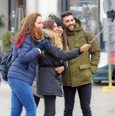 Três mulheres e um homem fazendo uma selfie em uma viagem de turismo