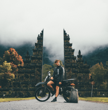 Um homem e sua moto em frente à um portal em Bali na Indonésia