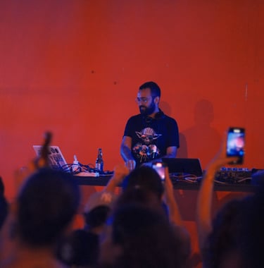 a man in a black shirt and a laptop on a stage djing with people taking pictures lebanon