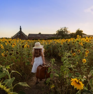 a little girl in a white dress and hat with a suitcase