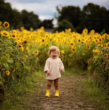 a toddler standing in a field of sunflowers