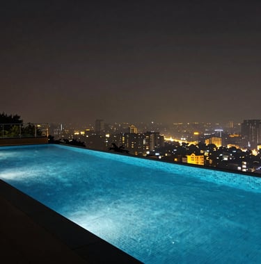 A professional architectural photograph of a sleek, modern infinity pool at night overlooking the city lights of Pune, featuring deep blue water and golden ambient lighting.