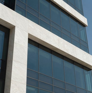 A close-up shot of architectural details of a luxury building facade. The materials include polished white stone and dark blue tinted glass. The style is ultra-modern and minimalistic under clear daylight in a Middle Eastern setting.