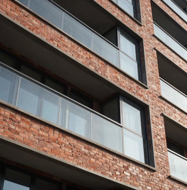 A close-up architectural detail shot of a premium facade with high-quality brick and glass finish, emphasizing the construction quality and modern design of a South Asian development.