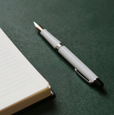A close-up photograph of a professional journal and a minimalist fountain pen resting on a dark green textured surface. The scene is lit by soft, natural morning light, evoking a sense of calm and intellectual focus.