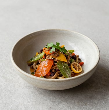 High-end culinary photography showing a modern interpretation of a classic South American dish. Ingredients are vibrant and fresh, served in a handmade ceramic bowl. Natural light, minimalist composition.