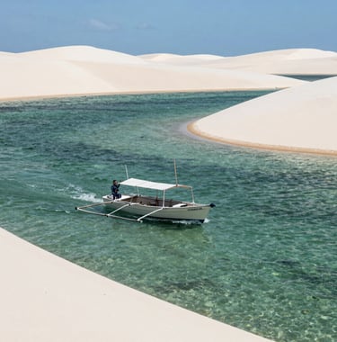 Action shot of a small boat navigating the crystal clear lagoons of Lençóis Maranhenses, bright sunlight, vast white sand dunes, South American / Brazilian nature.